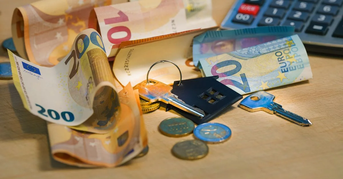 Les billets et pièces en euros avec des clés de maison sur une table symbolisent la finance et l'immobilier.