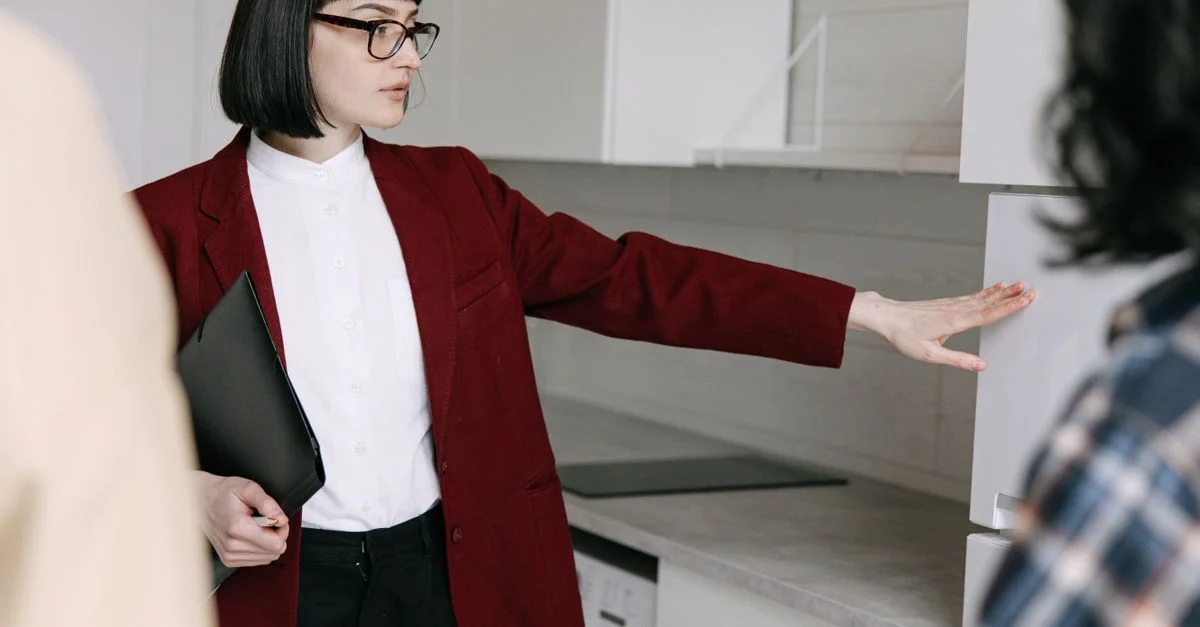 Une agente immobilière montre une cuisine moderne à des acheteurs potentiels dans un appartement.