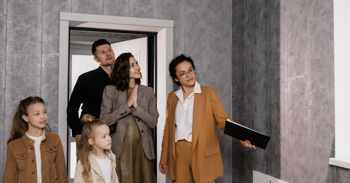 Une famille avec des enfants visite une nouvelle maison guidée par un agent immobilier. Idéal pour des thèmes immobiliers.