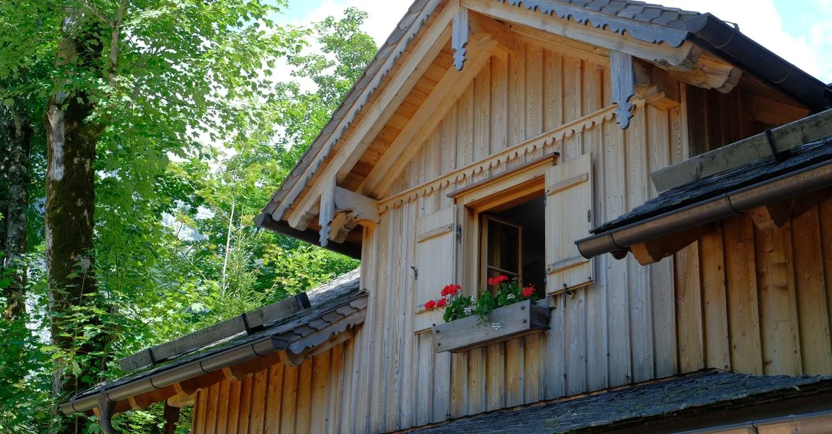 Belle maison en bois à Altaussee, en Autriche, avec des fleurs rouges dans une jardinière. Ambiance estivale sereine.