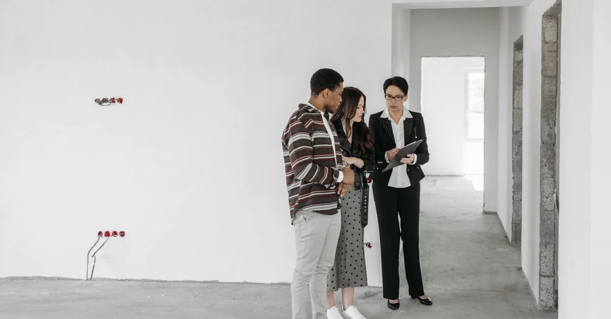 Un couple et un agent immobilier discutent des détails dans une propriété inachevée. Idéal pour des thèmes immobiliers.