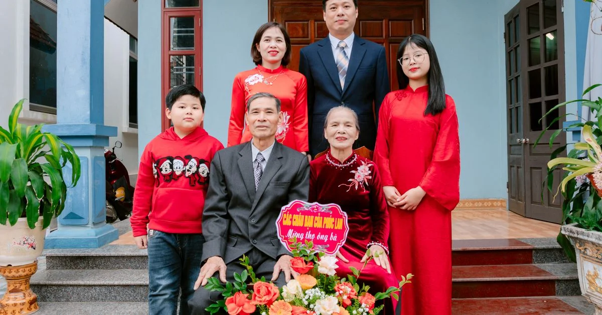 Une famille intergénérationnelle portant des vêtements traditionnels vietnamiens posant en plein air.