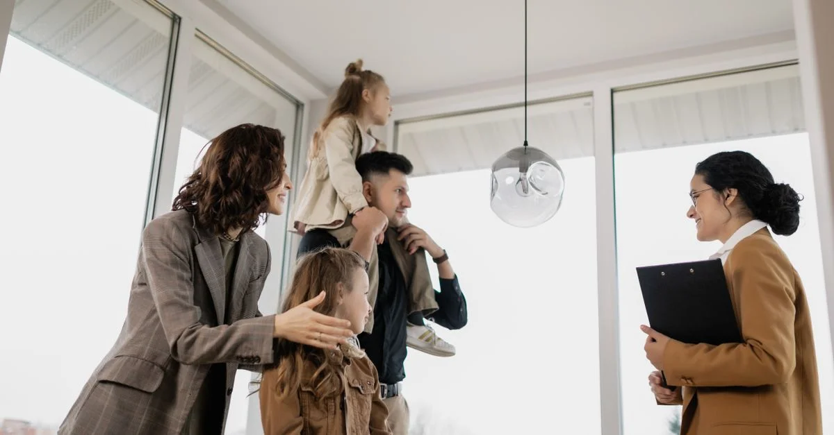 Une famille avec des enfants visite avec enthousiasme une maison moderne guidée par un agent immobilier.
