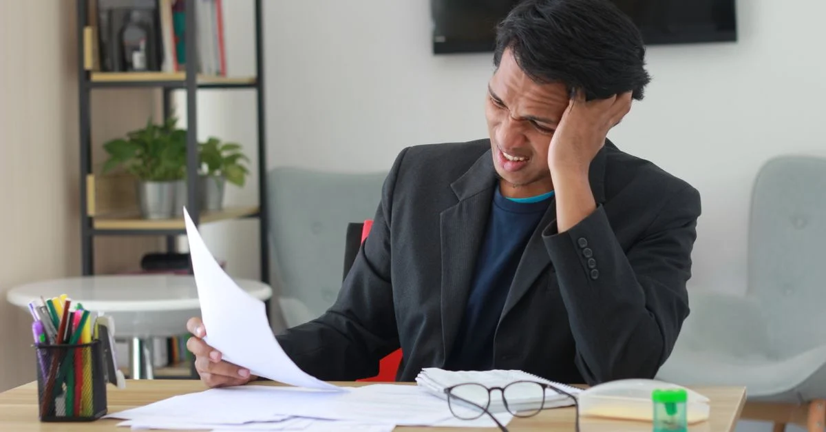Un homme d'affaires dans un bureau éprouvant du stress en révisant des documents.